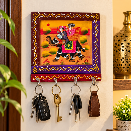 Hand-painted wooden key holder 
Square wall panel with a colorful painted border
Indian folk art artwork on a handcrafted wooden surface
Metal hooks arranged in a row for hanging keys
Compact wall-mounted key holder measuring 6 × 6 inches
Decorative accent for entryways, hallways and kitchens
Uphar Handicrafts