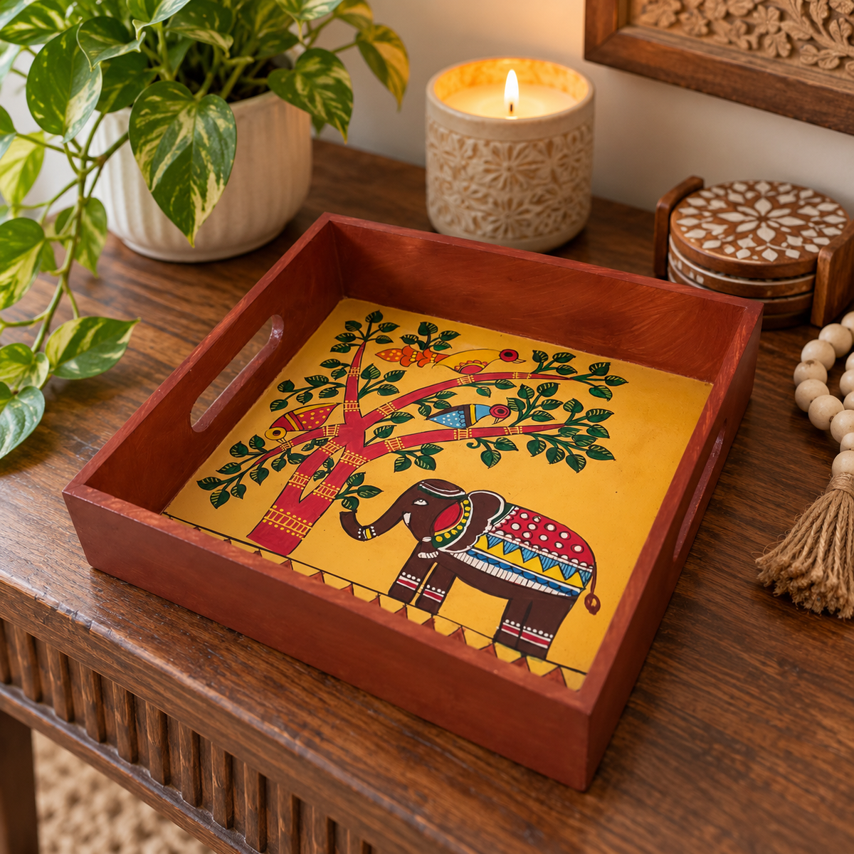 Decorative wooden tray with hand-painted elephant and tree artwork
Traditional folk art design on a square serving tray
Polished wooden border with cut-out handles on both sides
Handcrafted and hand-painted Indian-inspired home accessory
Suitable for table decoration, puja items and festive displays
A thoughtful handmade gift for housewarmings and celebrations
Uphar Handicrafts