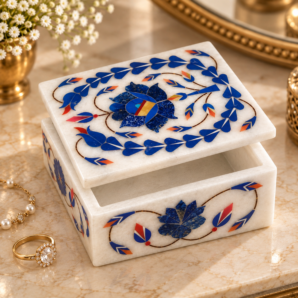 Indian handcrafted marble trinket box
White marble with hand-inlaid stone work
Rectangular design with a decorative lid
Floral and vine motifs on top and sides
Polished natural marble finish
Traditional Mughal-inspired jewelry storage
Uphar Handicrafts