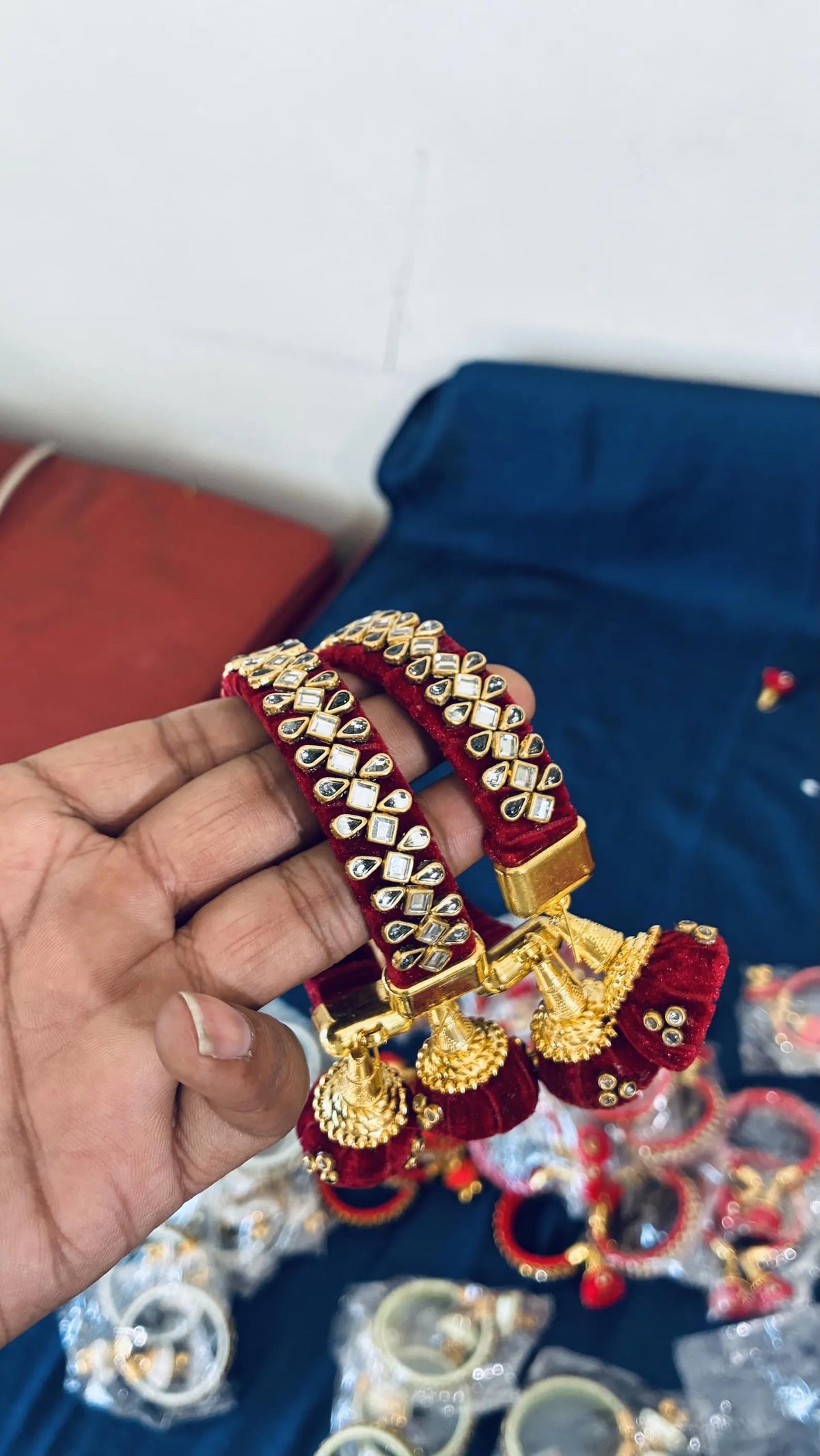 Maroon silk thread bangles with Kundan stonework
Gold-tone embellishments decorate the bangle surface
Jhumka latkan provides a hanging ornamental detail
Metal base covered with silk thread wrapping
Set of two traditional Indian bangles
Festive jewelry for traditional dressing
Uphar Handicrafts