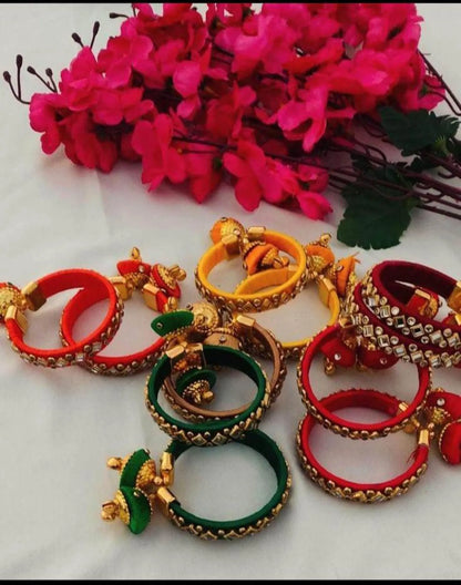 Multicolor silk thread bangles with Kundan detailing
Set of two traditional decorative bangles
Gold-tone embellishments on the thread-wrapped surface
Dangling jhumka latkan adds ornamental movement
Push-open clasp design
Indian traditional jewelry for celebrations
Uphar Handicrafts
