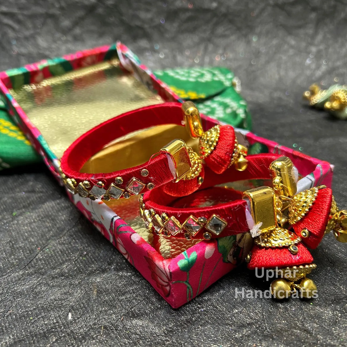 Red Traditional Indian silk thread bangle set
Kundan stones with gold-tone decorative embellishments
Jhumka latkan hangs from each bangle design
Set includes two matching bangles
Standard adult size with push-open closure
Decorative jewelry for festive celebrations
Uphar Handicrafts