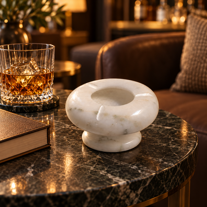 Round ashtray made from natural white marble
Polished surface with natural grey veining
Deep center bowl for collecting cigarette ash
Three cigarette rest slots around the rim
Raised pedestal base with a rounded design
Minimalist accessory for tables and desks
Uphar Handicrafts