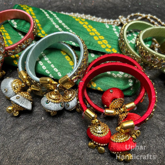 Handmade silk thread bangles with Kundan stones
Set of two traditional Indian jewelry bangles
Gold-tone embellishments with decorative detailing
Dangling jhumka latkan attached to the bangles
Metal base wrapped in smooth silk thread
Traditional jewelry for festive and wedding outfits
Uphar Handicrafts
