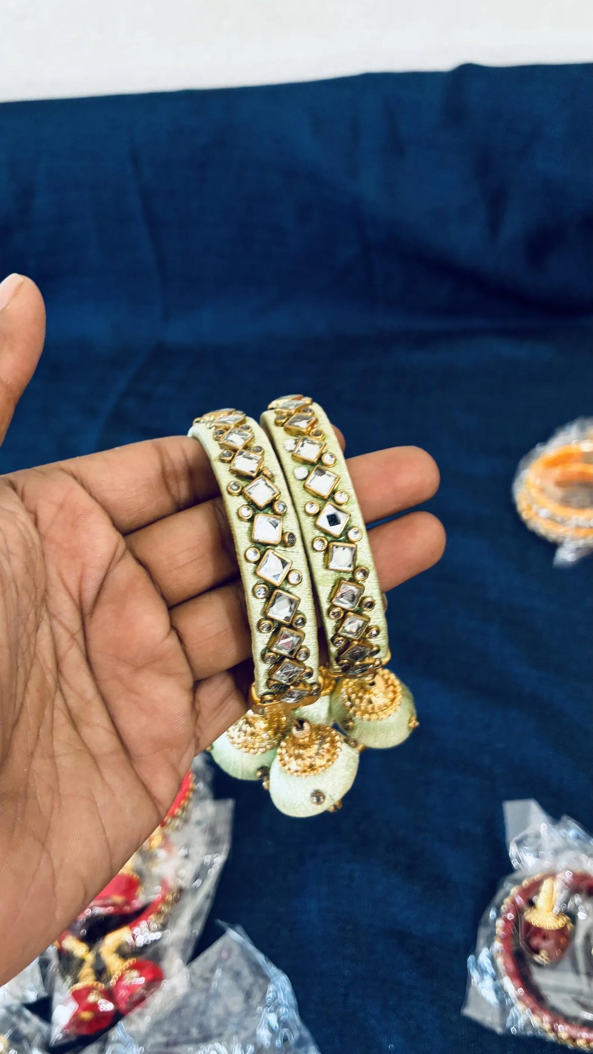 White silk thread bangle color options
Kundan stones paired with gold-tone embellishments
Decorative jhumka latkan on the bangle design
Metal base wrapped with smooth silk thread
Traditional Indian jewelry set of two
Suitable for festive and celebratory outfits
Uphar Handicrafts